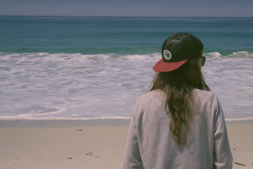 girl's back standing in front of the ocean