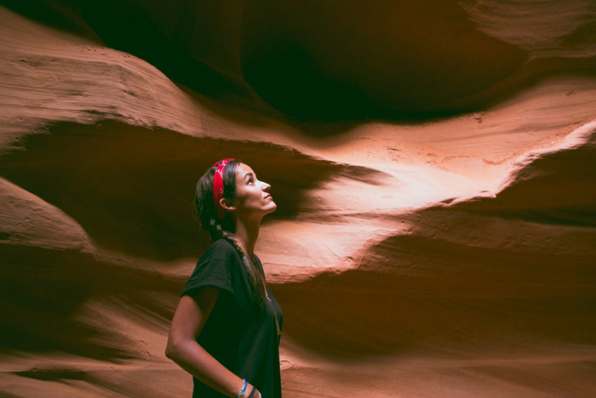 girl with red bandana and black shirt looking up inside the antelope canyon
