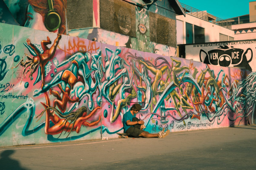 wall full of graffiti with skater sitting down