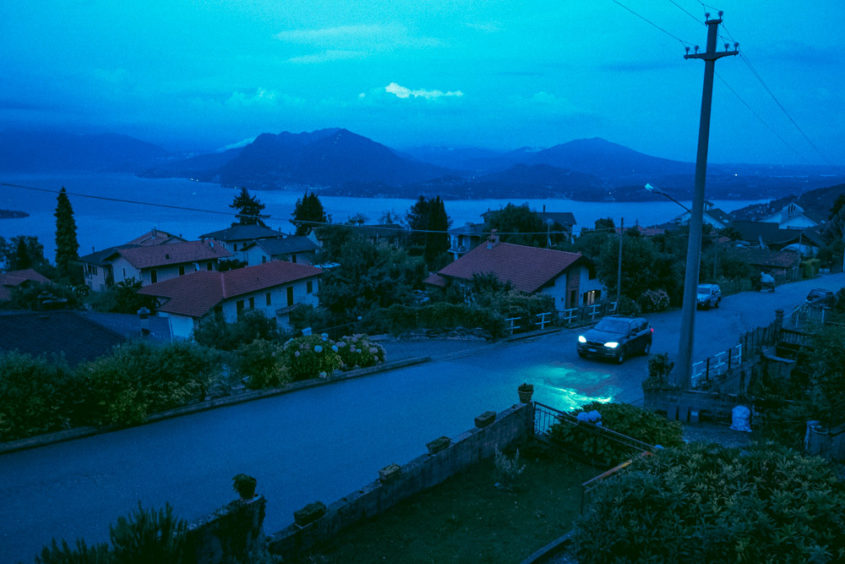 view from window of road with car and mountains and lake in the back