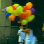 Woman with colourful balloons walking the streets