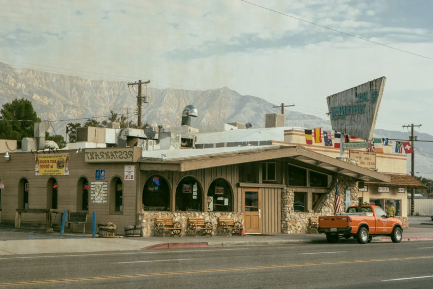 town with orange truck in front of restaurant and mountains in the background