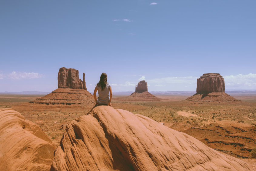 girl seating on rock looking at the monument valley view